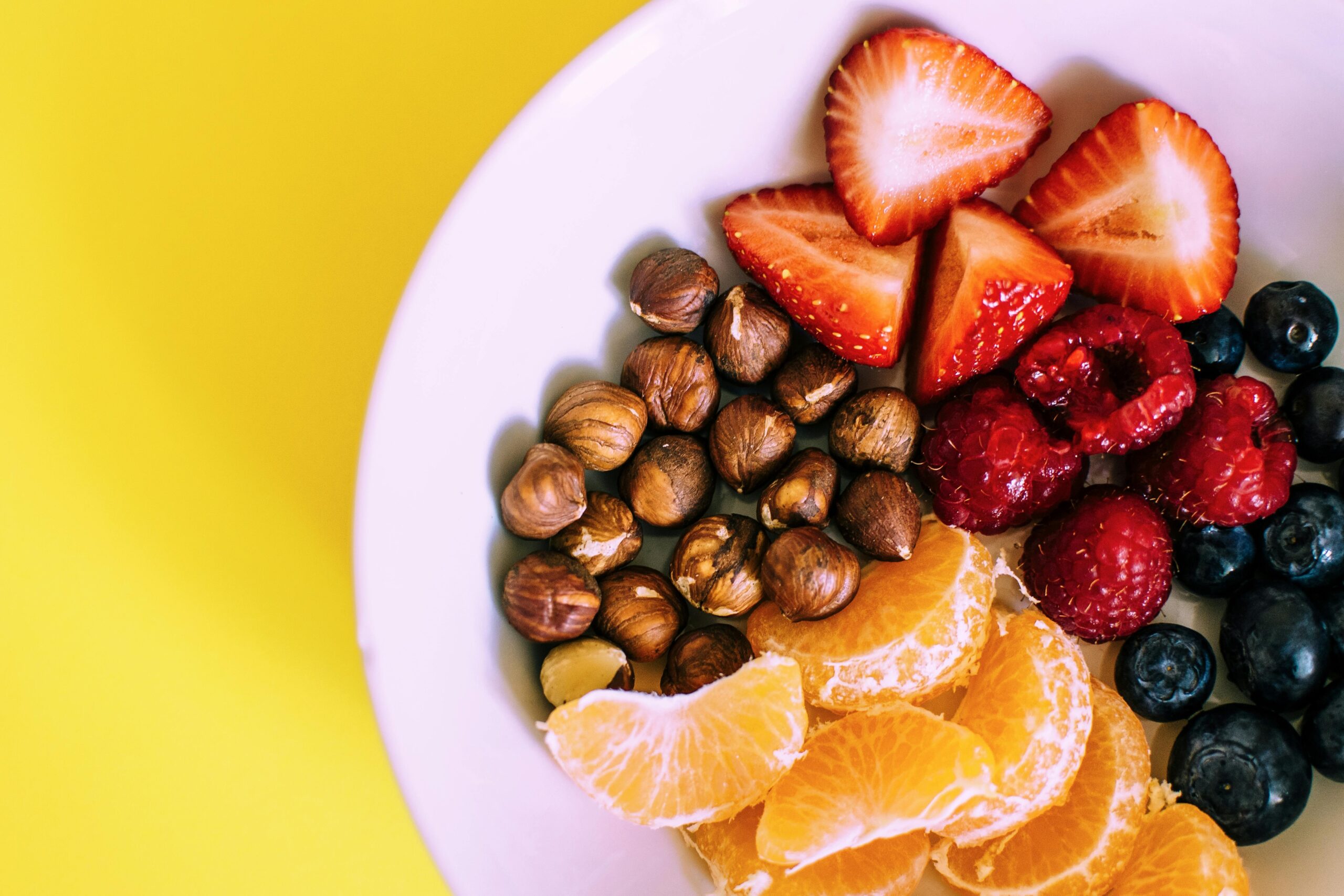 A plate filled with fresh berries, almonds, and avocado slices, representing healthy snacking ingredients.