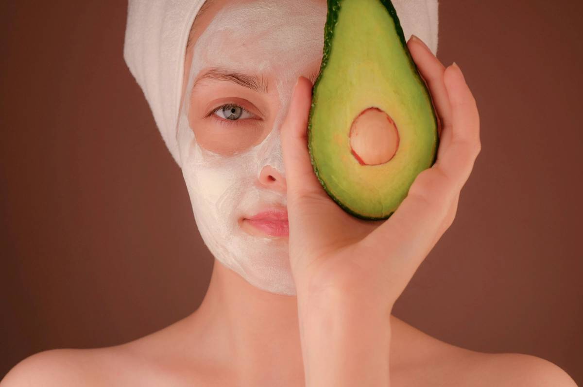 Portrait of woman holding bowl of organic stone fruits with glowing skin visible.
