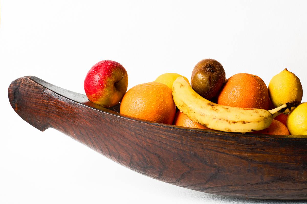 A bowl of mixed organic nuts and dried fruits next to a smoothie glass